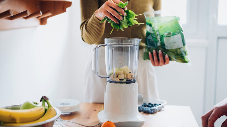 Person preparing smoothie in a blender