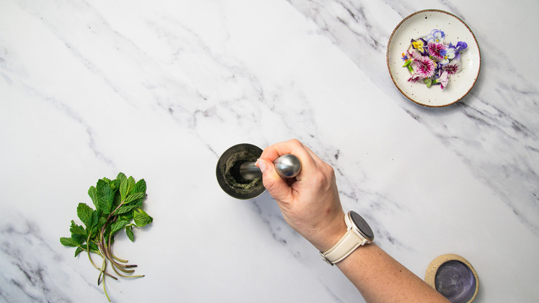 Muddling mint and sugar in shaker