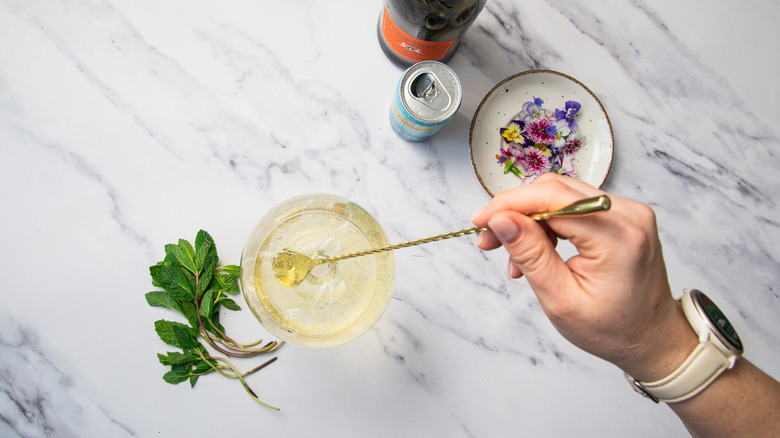 Stirring Hugo Spritz cocktail in glass