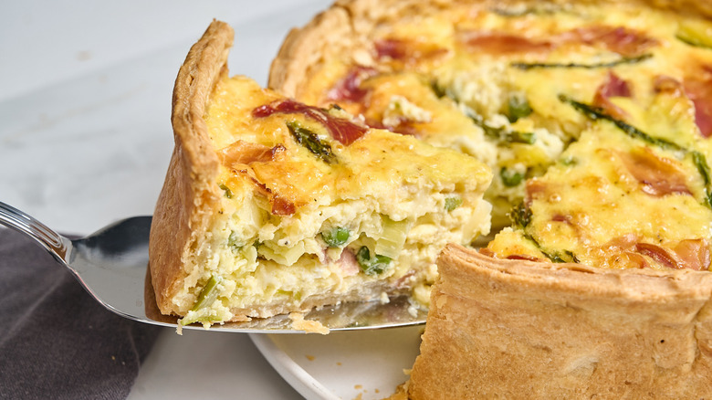 lifting a slice of quiche supreme out of quiche