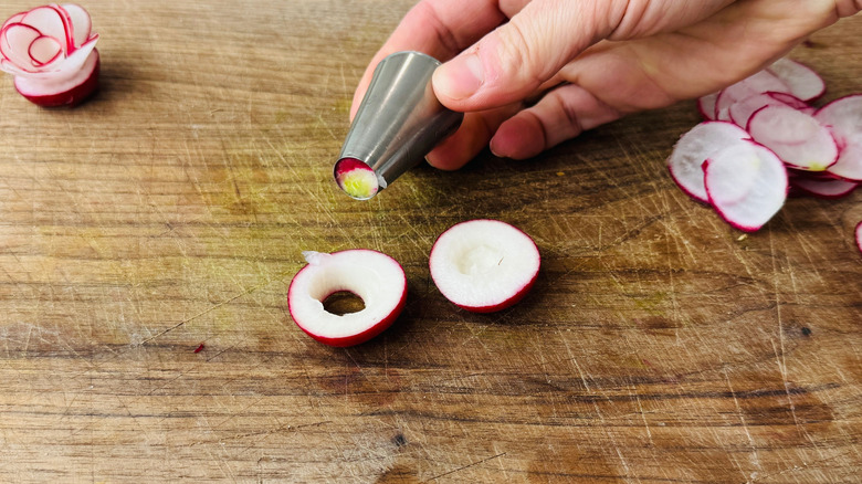 Hand holding piping tip over radish slice
