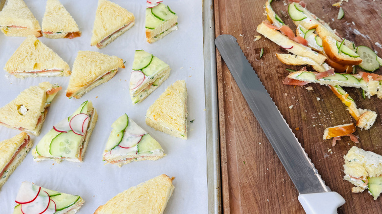 Triangle tea sandwiches next to knife and sandwich crusts