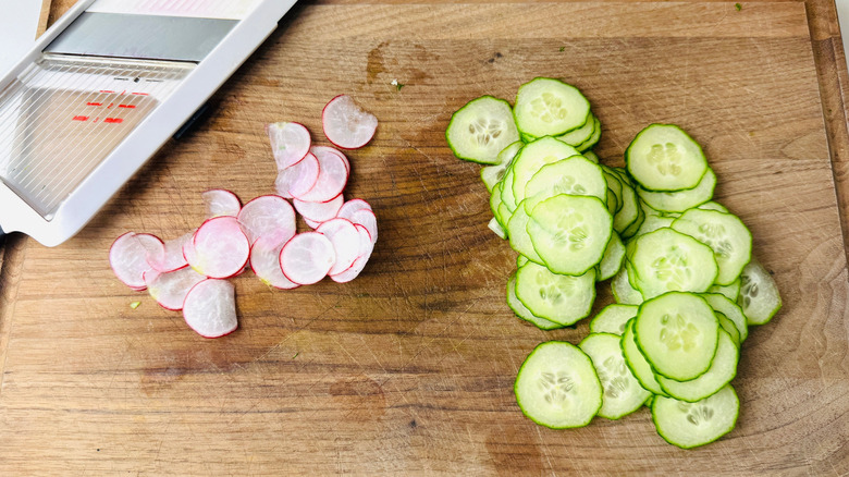 Thinly sliced radishes and cucumber on wooden board