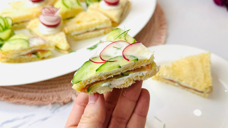 Hand holding cucumber and radish tea sandwich