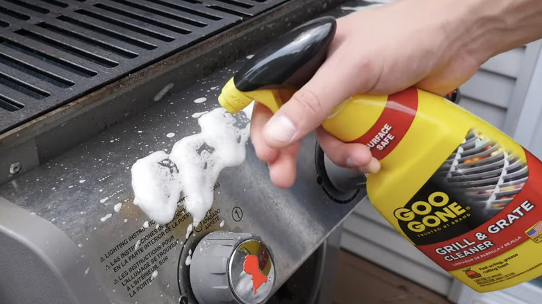 A bottle of Goo Gone Grill and Grate Cleaner in front of dirty grill grates
