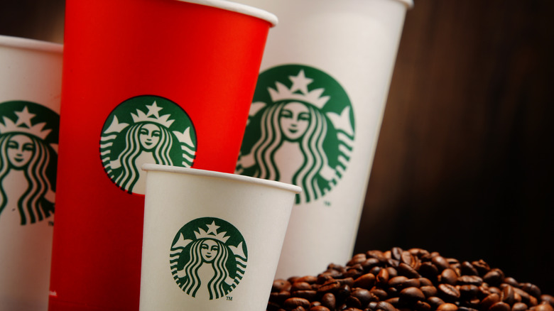 Starbucks cups beside coffee beans