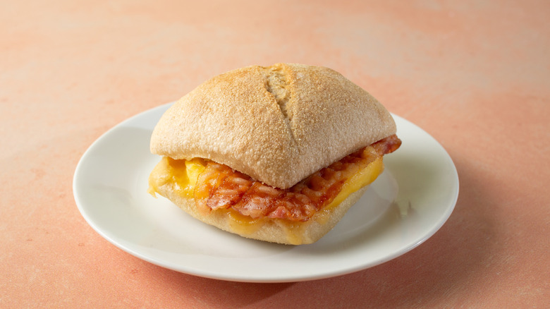 Bacon, gouda and egg breakfast sandwich on a white plate