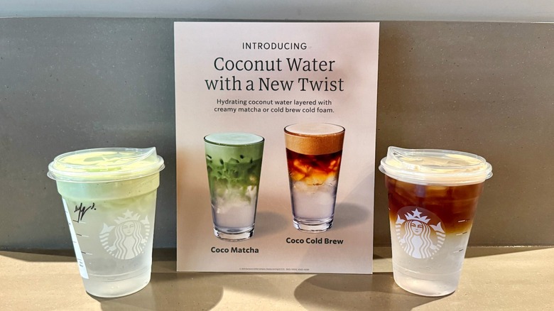 Starbucks Coco Matcha and Coco Cold Brew next to sign promoting the new drinks