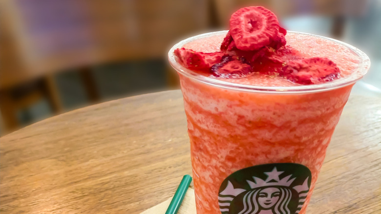A plastic cup of blended strawberry lemonade topped with freeze dried strawberries at Starbucks
