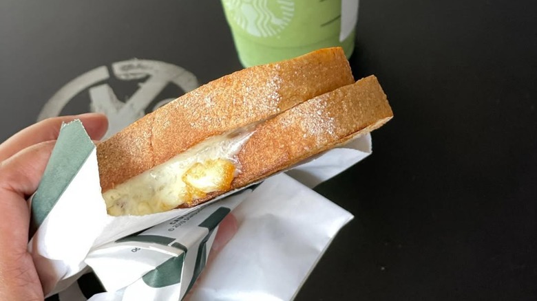 Someone holds up a grilled cheese from Starbucks