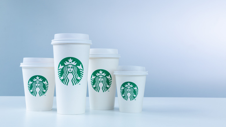 A range of different size Starbucks cups, including a kids size, in front of a white background