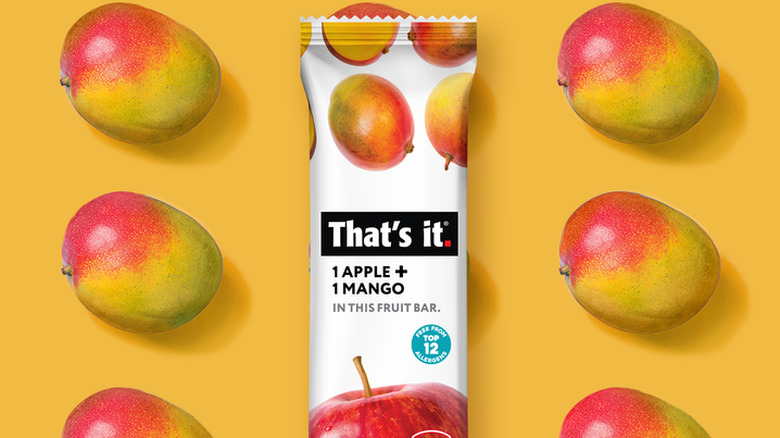 A That's It Apple and Mango bar against a yellow background with mangoes