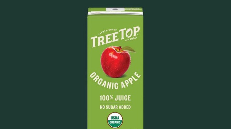 A carton of Tree Top Organic Apple Juice against a dark green Starbucks background
