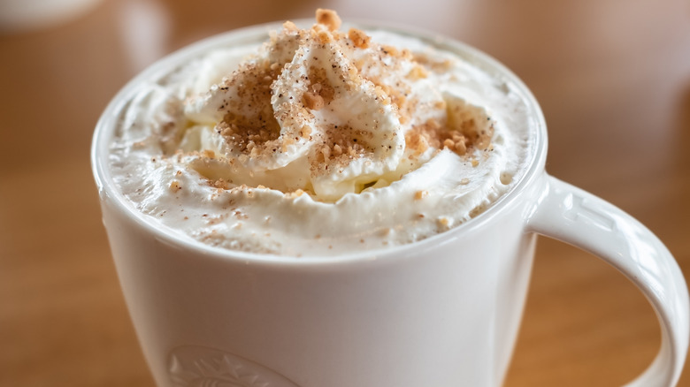 A Starbucks mug topped with whipped cream and brown butter topping