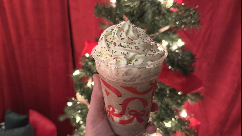 Frozen Peppermint Hot Chocolate held up in front of a Christmas tree