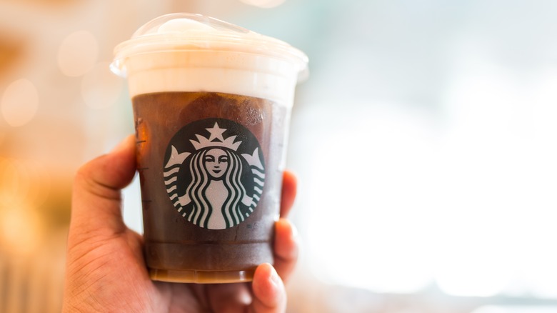 A hand holding a Starbucks drink with cold foam