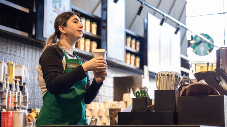 Starbucks barista holding drink behind store counter