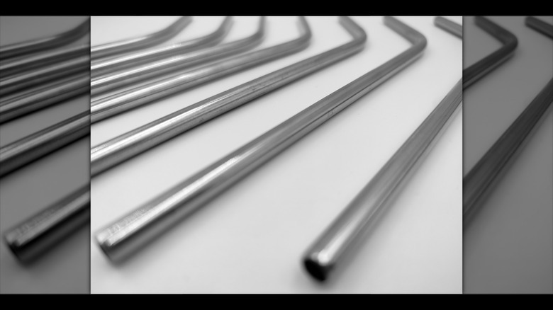 Mirrored image of stainless steel straws on white background close up shot