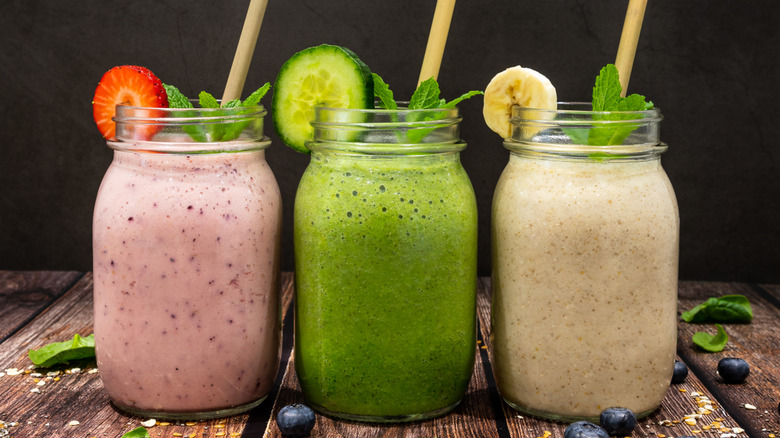 Pink, green, and yellow smoothies inside glass jars with straws