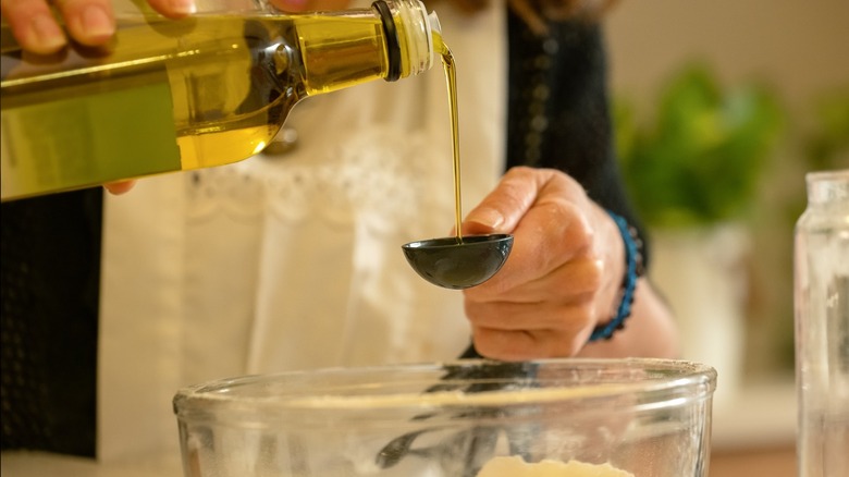 Closeup of person adding olive oil to mixing bowl