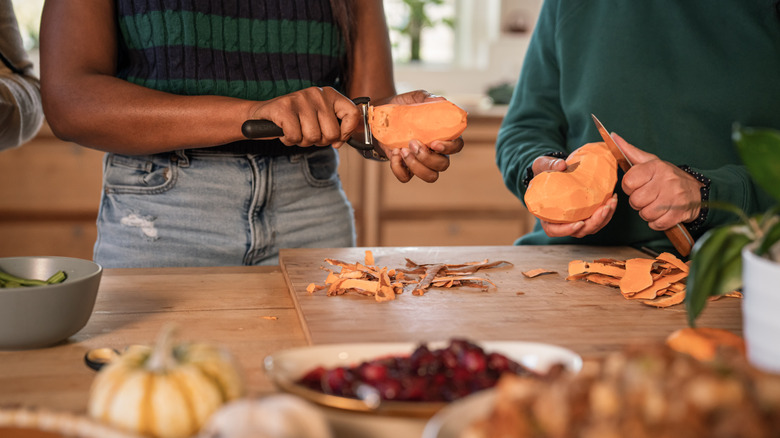 Two people in green shirts peel and slice sweet potatoes