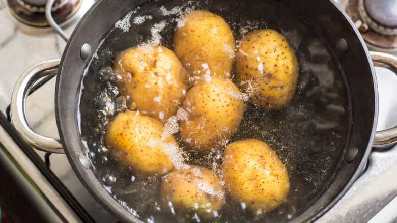 Yellow, skin-on potatoes boiling in a pot