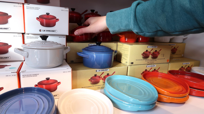 Le Creuset cookware and product boxes with hand reaching for product
