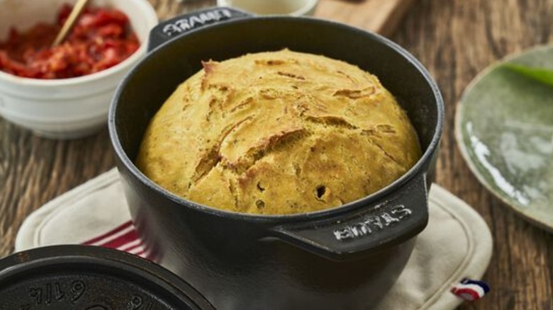 bread inside black Staub dutch oven on wood table