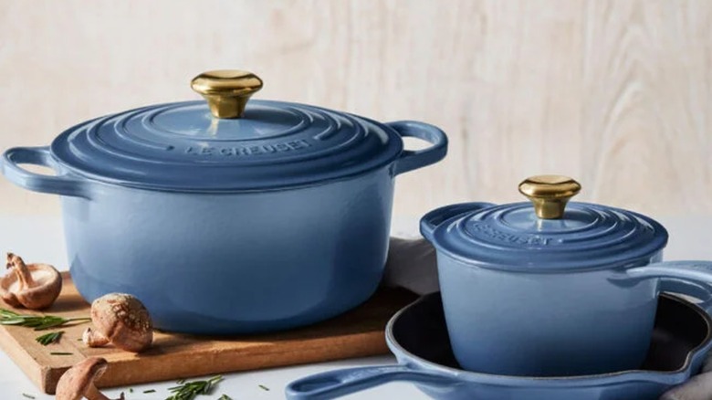 Collection of Le Creuset cookware in blue on white table