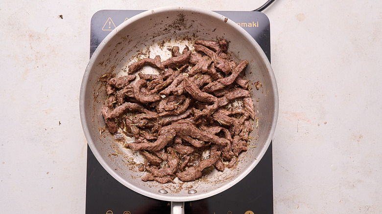 seasoning steak in a skillet