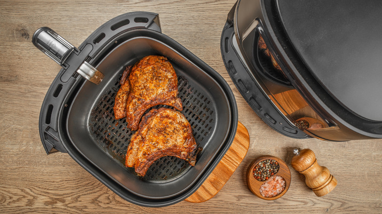 Two cooked ribeye steaks in basket of air fryer