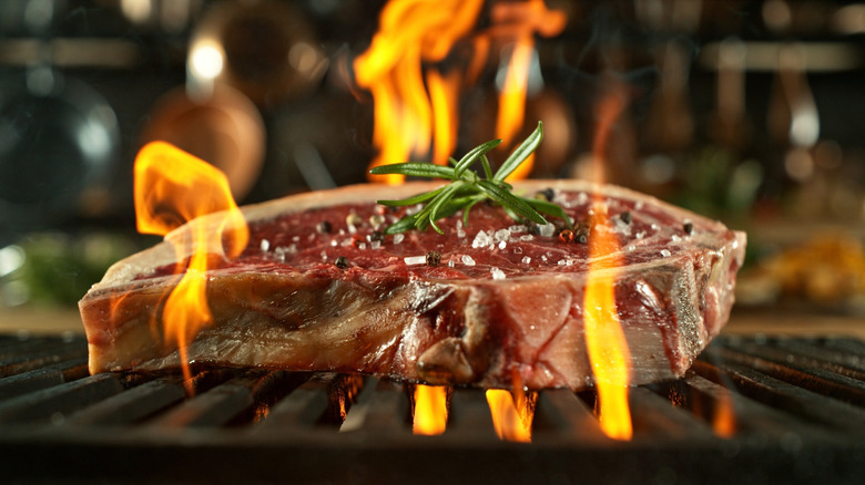grilling steak over flames