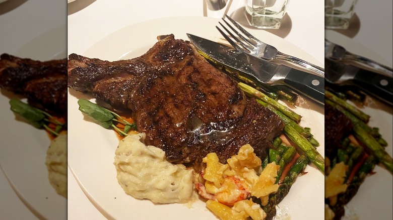 Grilled ribeye steak from The Capital Grille on plate next to mashed potatoes and roasted vegetables