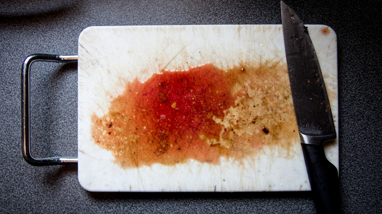 A white cutting board covered in juices from meat that had been cut on it
