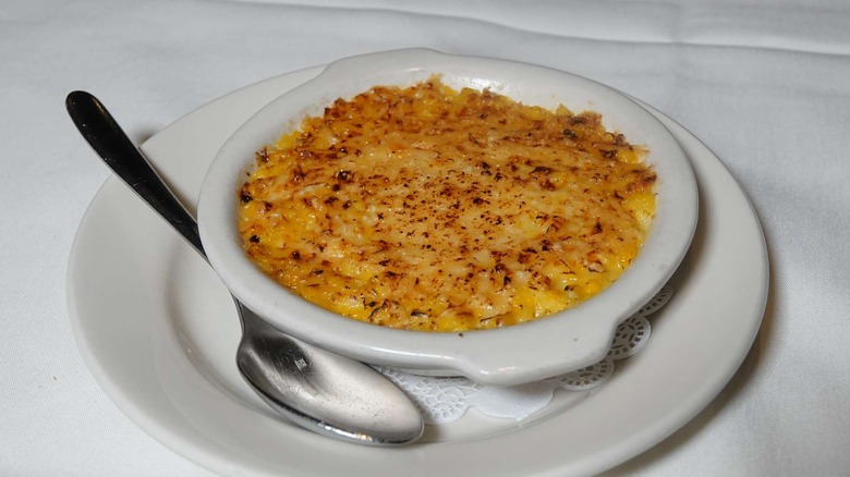 Creamed corn in white bowl on white plate with spoon