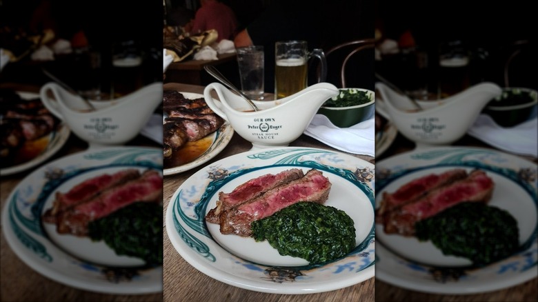 Plate of sliced steak and creamed spinach on restaurant table