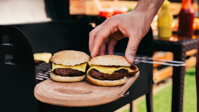A man placing burgers from the grill onto buns