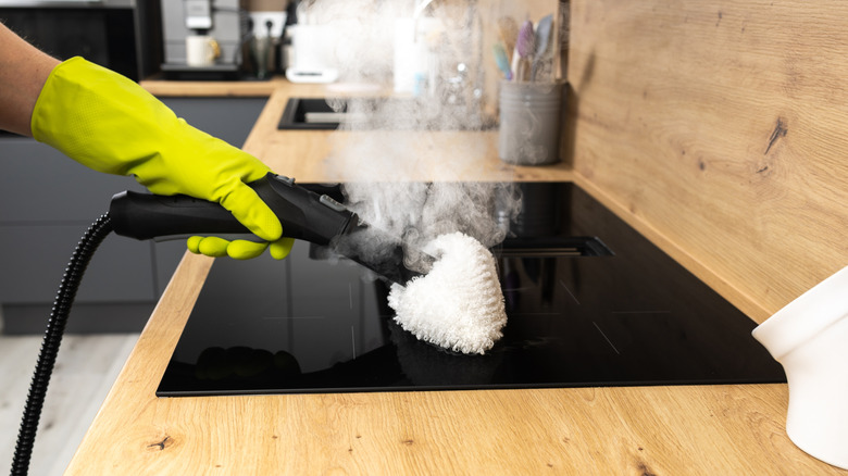person using steam cleaner on stove