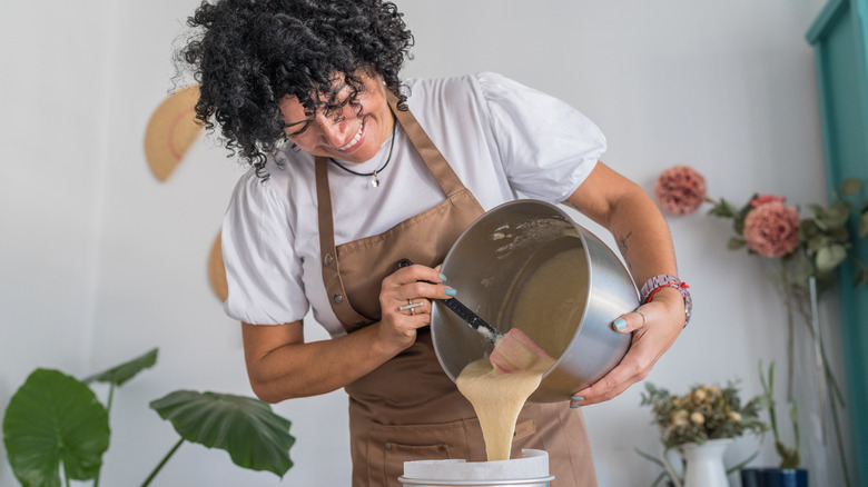 baker pouring cake batter from a metal mixing bowl