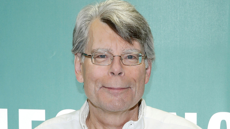 Stephen King smiling in white shirt with glasses