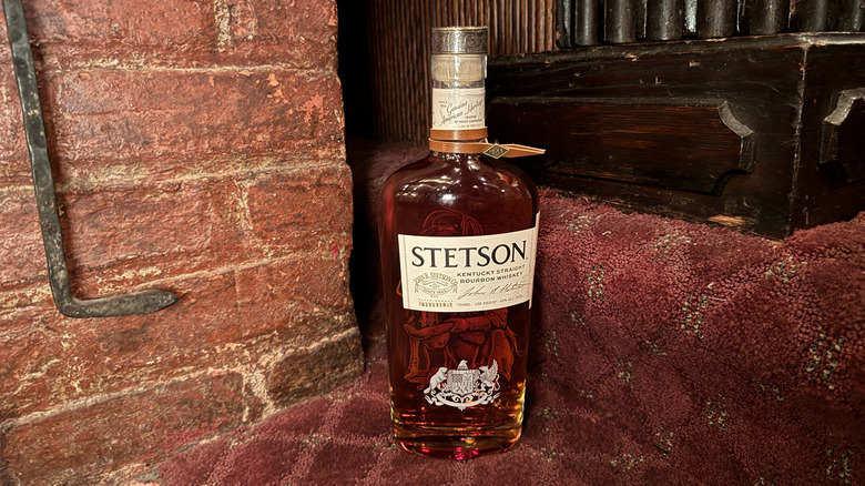 Bottle of Stetson Bourbon on red carpet stairs, brick wall and wood in background