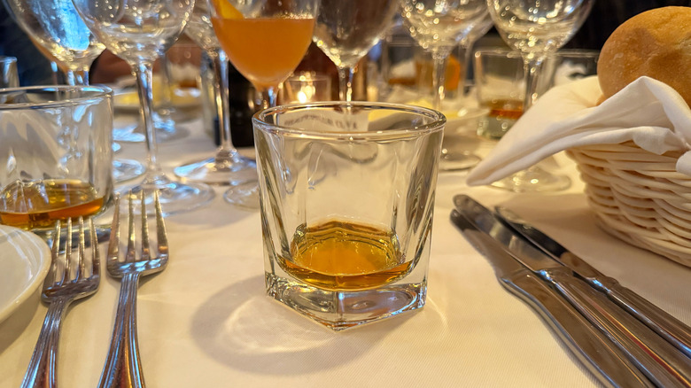 Glass of Stetson Bourbon on dining table, cocktail, forks and knives in background