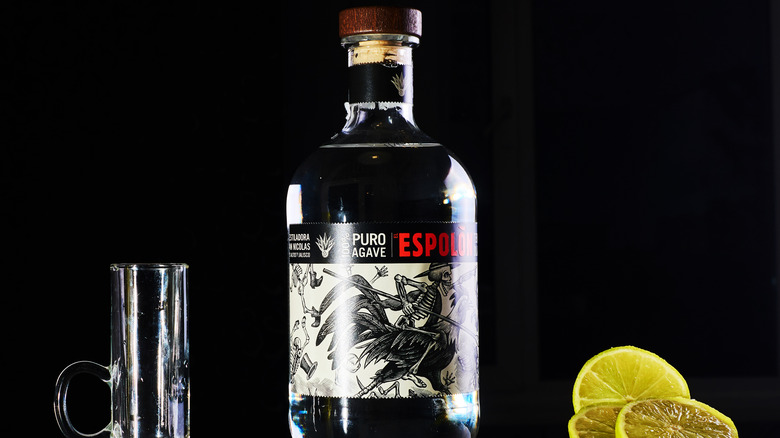 Bottle of Espolon tequila next to glass and lemons