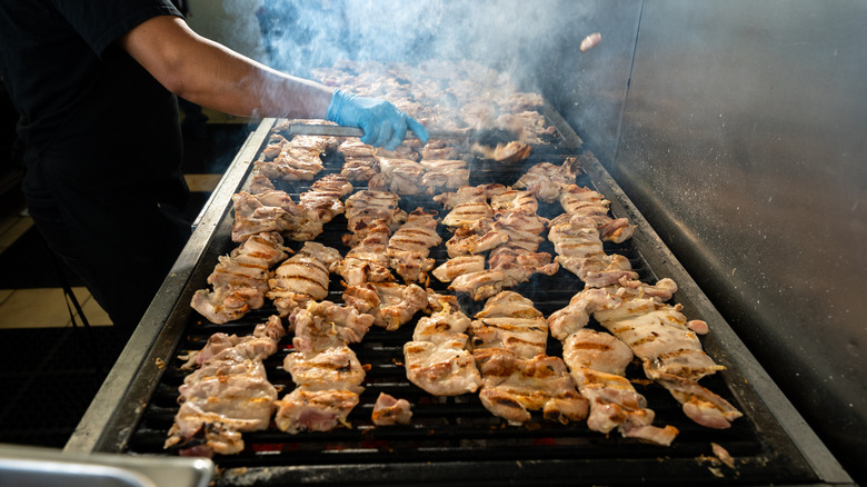 Cook grilling lots of chicken thighs