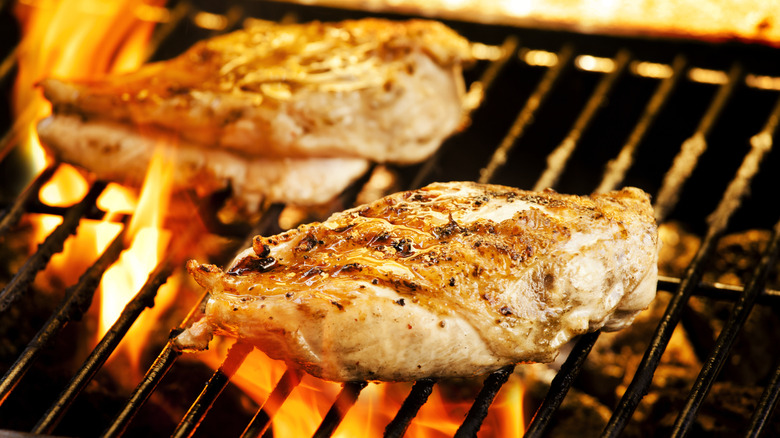 Two chicken breasts on a flaming grill