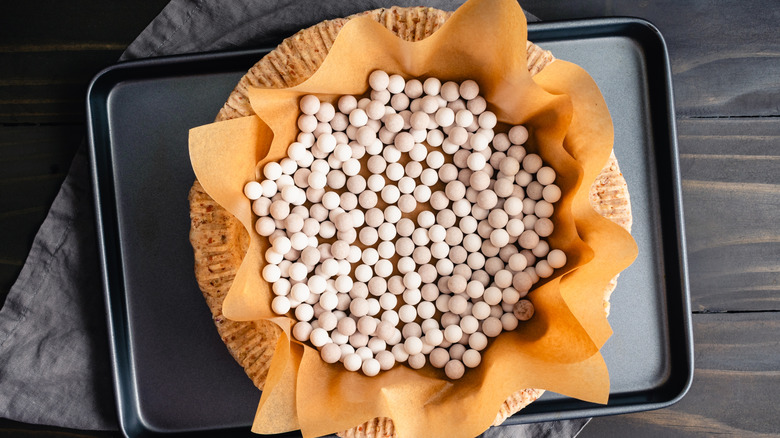 Overhead view of cooked pie crust with baking paper and pie weights