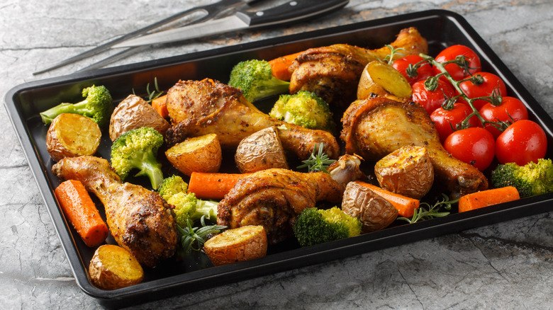 A sheet pan of chicken drumsticks and vegetables