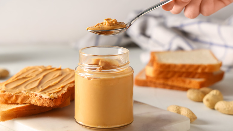 An open jar of peanut butter with toast in the background