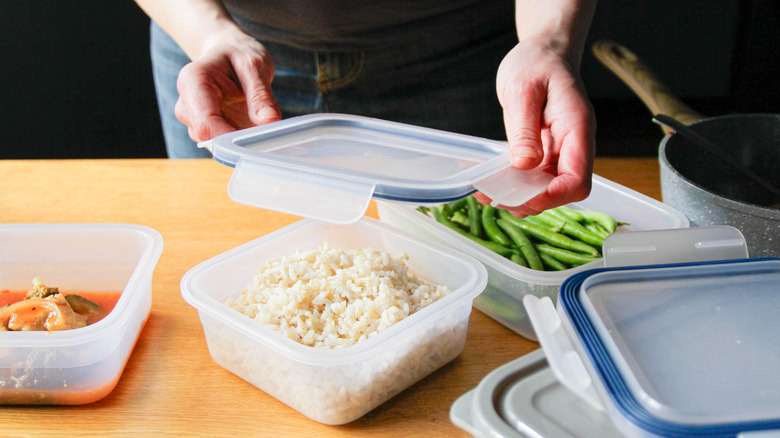 A person packing rice and other leftovers in containers
