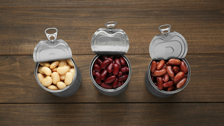 Three tin cans of beans opened with their lids propped back